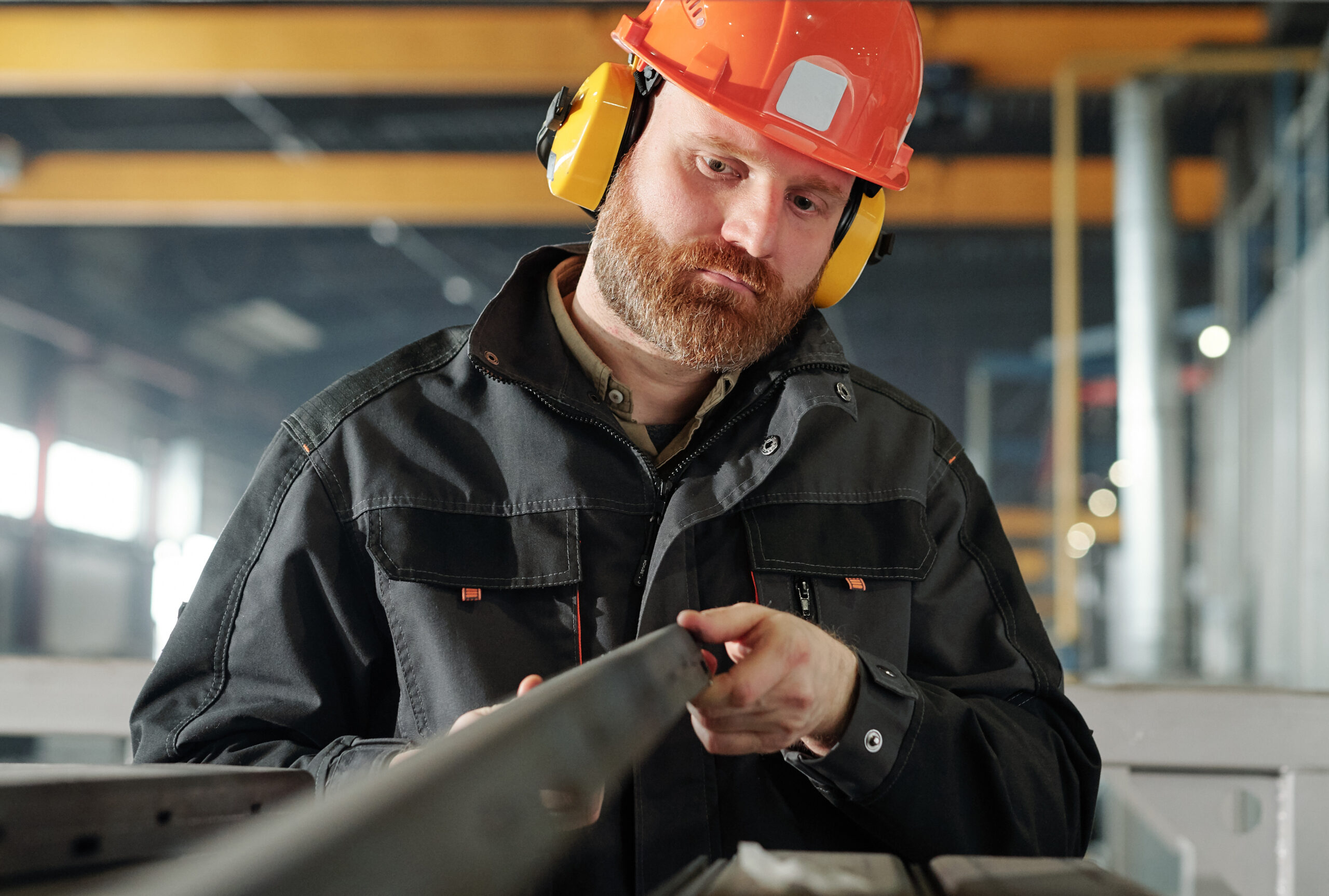 Young engineer of industrial plant looking at one of iron details.